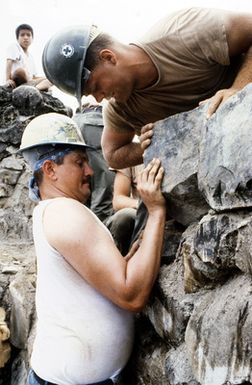 A sailor and a member of Naval Mobile Construction Battalion 4 do restoration work on the Spanish Wall, one of several civic action projects undertaken by the Seabees and crew members of the tank landing ship USS RACINE (LST 1191)