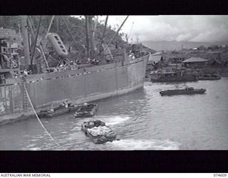 LAE AREA, NEW GUINEA. 6 JULY 1944. AMPHIBIOUS "DUKWS" BEING USED TO TRANSPORT GOODS AND SUPPLIES TO THE SHORE FROM AN AMERICAN "LIBERTY" SHIP ANCHORED IN THE HARBOUR
