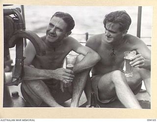 TINIAN, BOUGAINVILLE. 1945-07-18. FLIGHT LIEUTENANT N.C. SANDFORD (1) AND SERGEANT D.G. MCEROY (2), DRINKING BEER ON THE DECK OF THE MOTOR LAUNCH ML1327. THE VESSEL IS BEING USED BY THE ALLIED ..