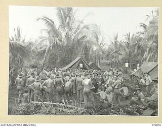 JACQUINOT BAY, NEW BRITAIN. 1944-11-11. TROOPS OF THE 14/32ND INFANTRY BATTALION, AND THE 5TH DIVISION HEADQUARTERS GATHER IN THE BATTALION AREA TO LISTEN TO THE RUNNING OF THE 1944 MELBOURNE CUP