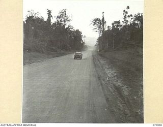 LAE - NADZAB ROAD, NEW GUINEA, 1944-03-09. THE BROAD GRAVELLED ROAD PASSING THROUGH CLEARED RAIN FOREST, 13 MILES FROM LAE. IT IS AN ALL WEATHER GRAVEL SURFACES ROAD CARRYING TWO LINES OF TRAFFIC ..