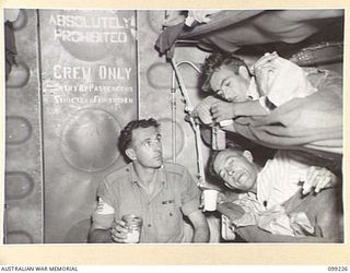 AIRBORNE, LAE, NEW GUINEA TO TOWNSVILLE, 1945-11-26. SERGEANT P.J. WILLIAMS, MEDICAL ORDERLY, ISSUING TEA TO PRIVATE A.J. MILLER AND PRIVATE E.L. GRUNDY, PATIENTS OF 2/7 GENERAL HOSPITAL WHO ARE ..