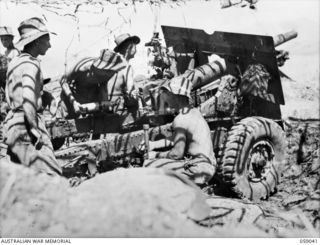 RAMU VALLEY, NEW GUINEA. Under camouflage "old faithful" a 25-pounder gun of F Troop, 54th Battery, 2/4th Australian Field Regiment about to send over harassing fire on Japanese positions in the ..