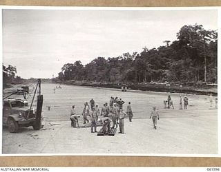 DREGER HARBOUR, NEW GUINEA. 1943-12-04. TROOPS OF THE 60TH UNITED STATES NAVAL CONSTRUCTION BATTALION (SEABEES) LAYING STEEL MATTING AT THE NORTH END OF THE NEW STRIP, WHICH, WHEN FINISHED, WILL BE ..