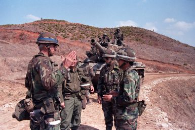 Exercise controllers from the 29th Infantry Brigade, Hawaii Army National Guard, discuss a dispute between competing forces with the commander of the 1ST Battalion, 14th Infantry Division, 25th Infantry Division, during the joint US/South Korean Exercise TEAM SPIRIT '86. In the background is an M60 tank