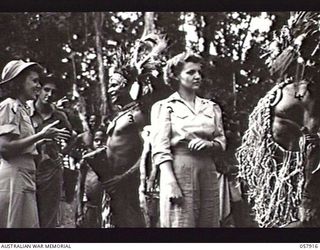 DOBODURA, NEW GUINEA. 1943-10-10. AMERICAN NURSING SISTERS HOLDING A SIGN LANGUAGE CONVERSATION WITH TWO NATIVE DANCERS. LEFT TO RIGHT: LIEUTENANT RITA SPIERS (OHIO); KAMBADI; LIEUTENANT DOROTHY ..